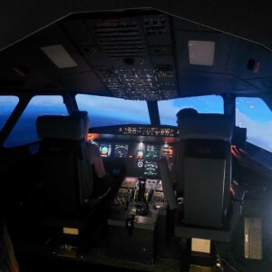 Nuoret aikuiset lentämässä Airbus A320-simulaattorilla kauniin sinisessä iltahetkessä.