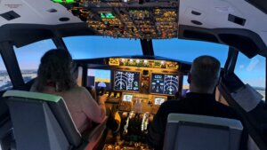 Nainen kapteenina ja mies perämiehenä lentämässä Boeing-simulaattorilla.
