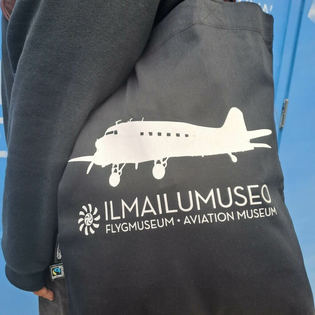 Ilmailumuseon musta kangaskassi henkilön olalla.