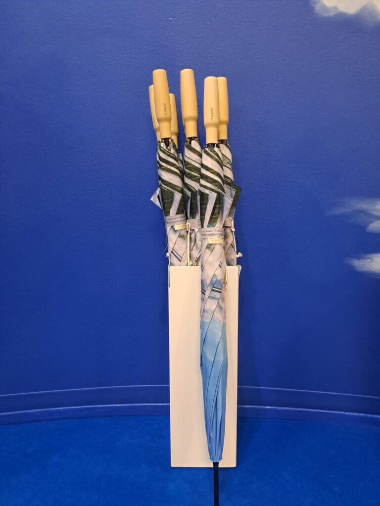 Suljettuja sateenvarjoja telineessä pystyssä ja yksi telineen ulkopuolella.