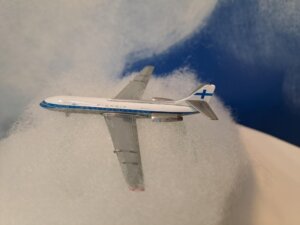 Finnair Caravelle pienoismalli pumpulisen "pilven" päällä, taustalla sini-valkoista pilvikuviota.