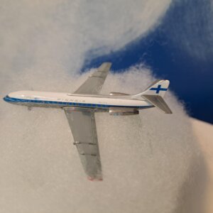 Finnair Caravelle pienoismalli pumpulisen "pilven" päällä, taustalla sini-valkoista pilvikuviota.