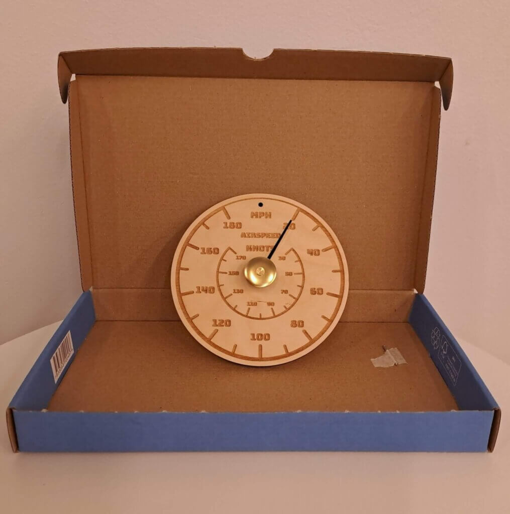 Ilmanopeusmittaria muistuttava saunamittari pahvisessa lahjalaatikossa.