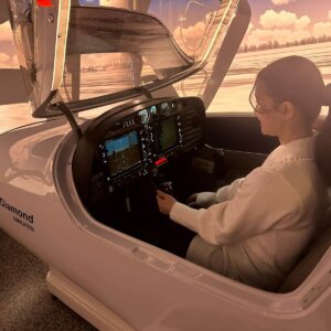 Nuori nainen iloisena Diamond DA-42 -simulaattorissa.