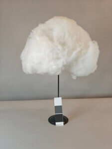 Valkoinen pilvi, muistuttaa hattaraa. Kuvattu jalustan päällä.