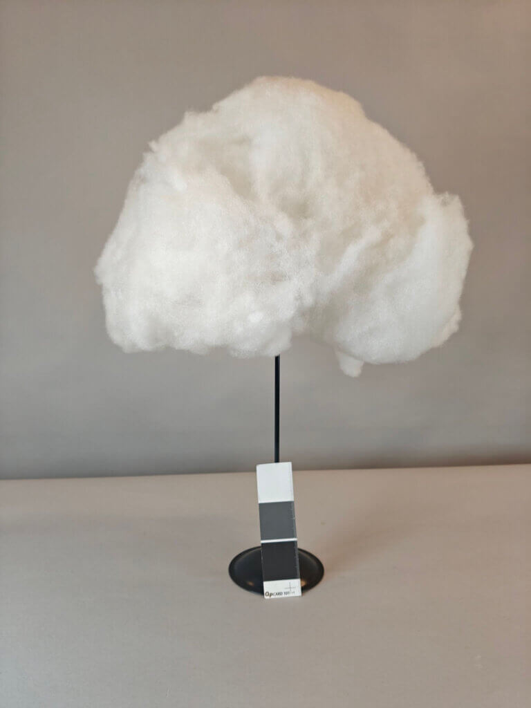 Valkoinen pilvi, muistuttaa hattaraa. Kuvattu jalustan päällä.