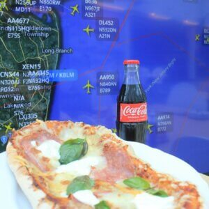 Etualalla pizza ja Coca-cola, taustalla Flight Radarin näkymä Nyw York Citysta.
