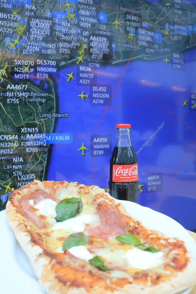 Etualalla pizza ja Coca-cola, taustalla Flight Radarin näkymä Nyw York Citysta.