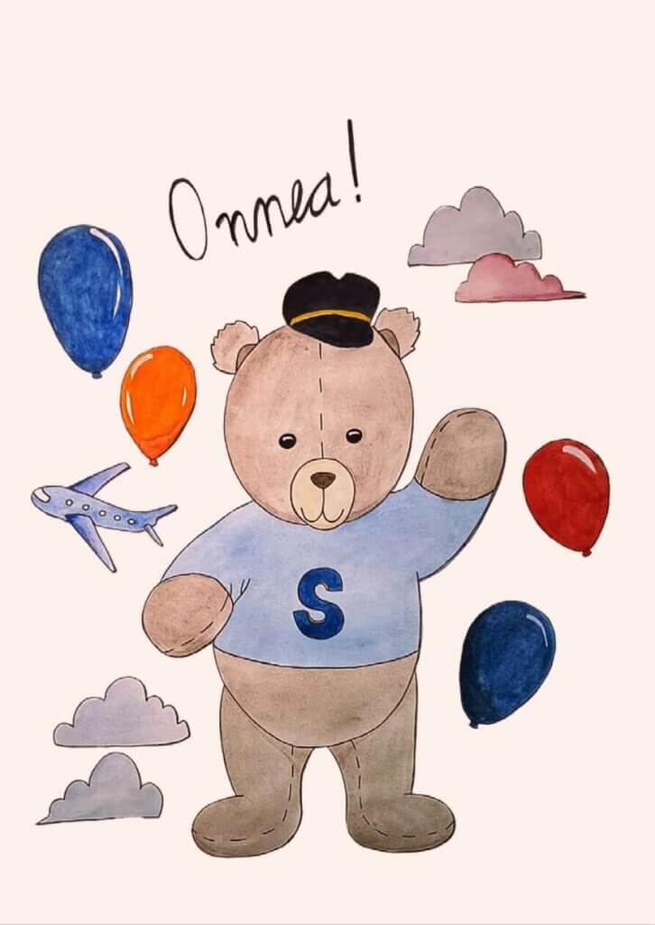 Postikortti, jossa Simppa-nalle vilkuttaa ja toivottaa "Onnea!" ilmailuaiheisella taustakuvituksella.